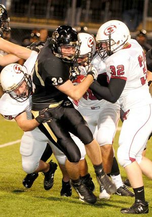 Bentonville senior Ben Nichols, No. 34, was dragged down by a trio of Springdale defenders during a kickoff during the Tigers’ 28-0 victory Friday.