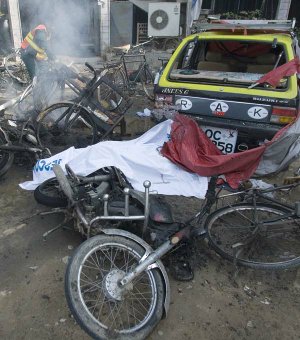 A rescue worker examines the scene after a suicide bombing Monday outside a bank in Rawalpindi, Pakistan.