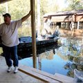 Mike Nash leans against a post in front of the boat he used to get to his house in the tiny Union Co...