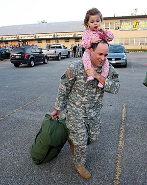 Gracie Massey, 2, rides atop her father's shoulders as Spec. Joseph Massey loads his duffle onto a bus as he and other soldiers from Arkansas National Guard's 875th Engineer Battalion prepare to leave Jonesboro Tuesday morning. 