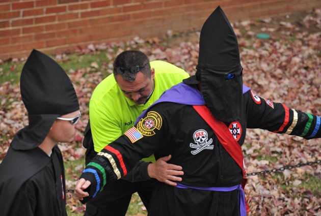 a-university-of-mississippi-police-officer-searches-a-member-of-the-ku-klux-klan-before-a-protest-on-the-steps-of-fulton-chapel-at-the-university-of-mississippi-in-oxford-miss-saturday-nov-21-2009