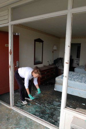 Housekeeper Twyla Davis cleans up broken glass Friday from Room 139 in the National Park Inn in Hot Springs, where a man was killed Thursday in a police shootout.