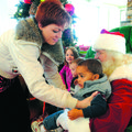 Lindsay Wallingford, left, puts son Jeremiah Wallingford, 2, on Santa’s lap for a family picture Sat...