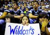 Yesenia Facundo, middle, holds a Wildcats sign as she sits with classmates Halle Roberts, right, and Emily Kemp, left, during the Springdale Har-Ber High School pep rally Friday in Wildcat Gym. Students from Bernice Young Elementary school in grades three through five who met their reading goal were able to attend the rally.
