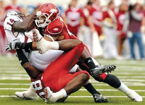 Arkansas linebacker Freddy Burton, top, and Damario Ambrose combine for a tackle on MIssissippi State backup quarterback Chris Relf during Saturday’s game in War Memorial Stadium in Little Rock.