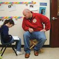 Delaney Reaves, 7, reads Friday to Chad Hicks, who is participating in Watch D.O.G.S. at the Benton ...