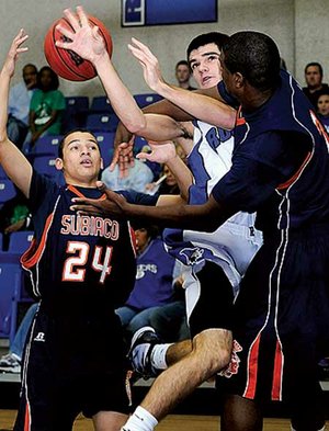Rogers High’s Wyatt Hively goes up for the shot as Subiaco Academy Keon Walters, right, and Mickell Salley block during the first half of Monday’s game in Rogers.
