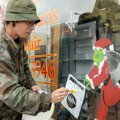Darrell Farmer touches up the Grinch on a window at Dave’s Appliance store in downtown Siloam Spring...