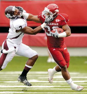 Arkansas tailback Dennis Johnson stiff-arms Mississippi State’s Robert Elliott on a kickoff return during the Razorbacks’ game Saturday in War Memorial Stadium in Little Rock.

