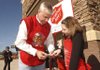 Rogers Mayor Steve Womack lets Salvation Army bell ringer Caitlyn Williford of Fayetteville select the first bill Wednesday to go into the donation kettle.