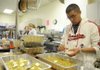 Jose Martinez, right, an Army private stationed at Fort Leonard Wood, Mo., prepares dressing Thursday at the First Baptist Church in Rogers. Martinez volunteered to help the church prepare and deliver 2,400 Thanksgiving meals across the area while visiting family in Rogers.