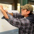 Ernie Hudgens tapes the dates for early voting to a window Friday in the Sugar Creek Center in Bella...
