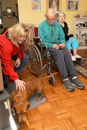 Jack and Melba Decker’s dog, Harvey, gets a dog treat from Bobbie Aldridge in their home in Bentonville on Saturday. Aldridge and her mother, Loretta DePriest, drive around the county once every two weeks to help feed pets whose owners have difficulty traveling to buy pet food.