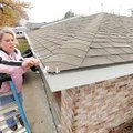 Cassie Kelley attaches LED holiday lights along the roofline of her Springdale home Sunday. “I shoul...