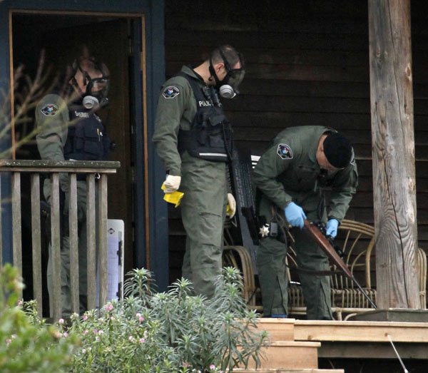 sheriffs-deputies-look-over-a-rifle-they-removed-from-a-home-where-a-suspect-in-the-slaying-of-four-police-officers-gunned-down-a-day-earlier-was-believed-to-have-been-monday