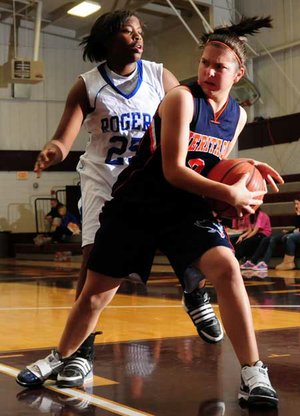 Rogers Heritage’s Ashley Ward, right, grabs a rebound in front of Rogers’ Taylor Strickland during Tuesday’s game in the Benton County Invitational Tournament in Siloam Springs.