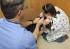 Dr. Doug Parker, left, veterinarian at Sugar Creek Animal Hospital in Bentonville, gives Jasper a vaccination Wednesday as vet technician Charlye Key holds the dog.
