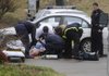 Fayetteville firefighters and paramedics from Central EMS prepare to transport Matthew L. Anderson Wednesday after he was shot by police while he allegedly tried to rob the Arvest Bank branch on Garland Avenue in Fayetteville.
