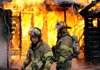 Rogers Fire Department Capt. Rob Taylor, right, and firefighter Pete Melnicki wait for water to be supplied to their hoses Wednesday at the scene of a vacant house fire on North “C” Street in Rogers. There were no injuries reported in the incident. 