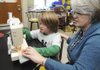 Christie Price, right, helps Kobie Johnson, 9, use a sewing machine to make a quilt Thursday in REACH class at Reagan Elementary School in Rogers. The students make the quilts and donate them to the Northwest Arkansas Children’s Shelter.