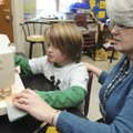 Christie Price, right, helps Kobie Johnson, 9, use a sewing machine to make a quilt Thursday in REAC...