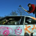 Ninth-grader Grant Bembenek takes a shot with a sledgehammer on a car Thursday outside Fayetteville’...