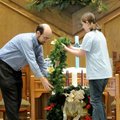 Tony Matthews and his daughter, Katie, 11, place the wreath around the Advent candles in a Hanging o...
