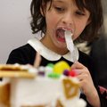 Anna Pittman, 6, of Fayetteville takes a lick of frosting Sunday while working on building a gingerb...