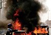 A Pakistani police officer stands near burning vehicles after a suicide bombing in Peshawar, Pakistan on Monday.