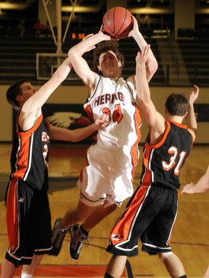 Rogers Heritage junior Thomas Moreland is fouled by Republic’s Ryan Mathis, left, and Josh Morrow during the second half Tuesday at Heritage High in Rogers. The War Eagles lost 40-37.