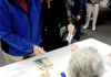 Richard and Jan Abbott present identification to election official Deanna Piatt at Bella Vista Christian Church in Bella Vista on Tuesday.