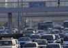 A pedestrian crosses above a traffic jam on Tuesday in Beijing. China’s auto production and sales each exceeded 1 million vehicles in November, a private research group said. 