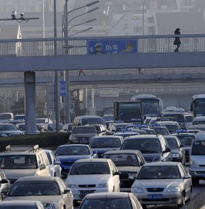 A pedestrian crosses above a traffic jam on Tuesday in Beijing. China’s auto production and sales each exceeded 1 million vehicles in November, a private research group said. 