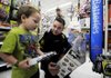 Springdale officer Tommy Wooten, right, helps Ethan Adams, 4, pick out a toy Tuesday at Walmart in Springdale during the annual Shop With a Cop event.