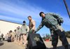 Lt. Col. Ken Kopp (right) passes a piece of luggage down the line as members of the 61st Airlift Squadron load gear in preparation for the unit’s deployment Wednesday from Little Rock Air Force Base in Jacksonville. 