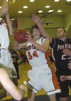 Rogers Heritage’s Thomas Moreland, center, drives to the basket in front of Pea Ridge’s Cameron Thompson during Thursday’s game in the Arvest Hoopfest Classic in Rogers.