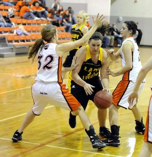 Prairie Grove senior Alex Myers, center, tries to get past Gravette’s Shelby Newell, right, and Jacy Alsup in the fourth quarter Friday in Gravette.