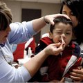Alma Mora of Springdale (right) holds her son, Julian Mora, 4, as nurse Tabitha Gibbs of Bentonville...