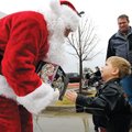 Luke Lancaster, 3, of Bella Vista hands Santa Claus a toy donation Saturday as his father, Ken, look...