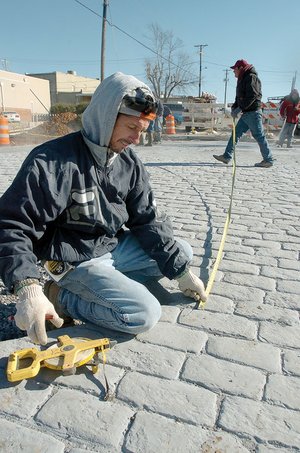 Frank Gonsalves with Ozark Patterned Concrete takes measurements Friday at the intersection of Second and Cherry streets during construction.
