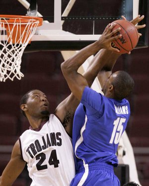 UALR’s Wayne Burton (left) blocks a shot by Memphis’ Elliot Williams during Saturday night’s game. The Trojans will try to get back on the winning track tonight in their Sun Belt Conference opener against South Alabama. 