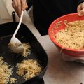 A member of the Congregation Etz Chaim Men’s Club scoops latke batter into hot oil during the group’...
