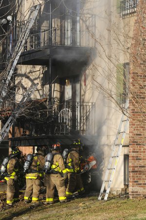 Fayetteville firefighters cut a vent hole Wednesday in the wall of an apartment building at The Vineyards on Garland in Fayetteville.