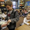 Jack Mason counts out $200 to Arvest Bank representative Sue Burk on Thursday. Second-graders at the...