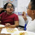 HOLIDAY PARTY
Lisbeth Rivas, left, teaches Jesus Barroso, right, how to eat with chopsticks Friday ...