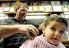 Carson Jackson, 4, gets his hair cut Saturday by Vic Bradford at Townzen’s Barbershop in downtown Rogers during the shop’s annual holiday fundraiser benefitting the Samaritan Community Center.