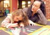 Alisha Chouinard watches Tuesday while her daughter, Dove Chouinard, 3, assembles and paints a Kwanzaa mat in the Children’s Library at the Bentonville Public Library.