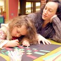 Alisha Chouinard watches Tuesday while her daughter, Dove Chouinard, 3, assembles and paints a Kwanz...