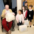 A group of young volunteers present Christmas care packages Tuesday to Clifford Richard at Concordia...