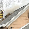 Bentonville firefighter Justin Scantlin cuts a hole to ventilate the roof during a house fire Sunday...